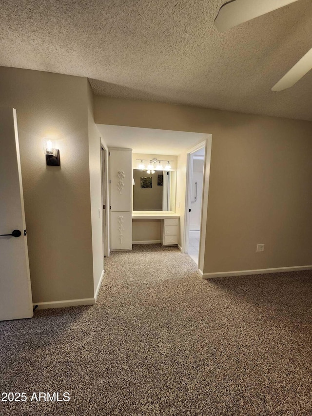 hallway featuring a chandelier, carpet floors, a textured ceiling, and baseboards