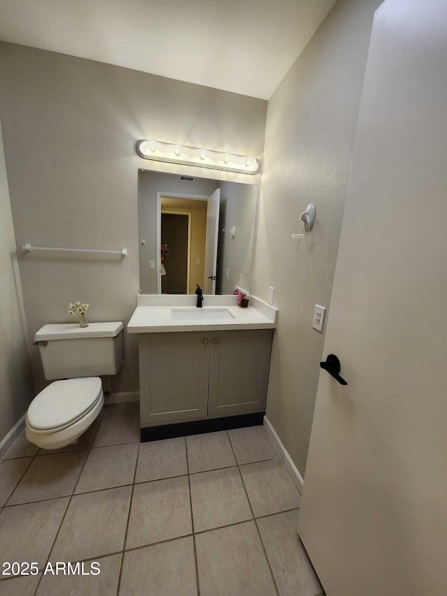 half bath with vanity, tile patterned floors, baseboards, and toilet