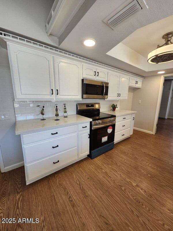 kitchen featuring baseboards, white cabinetry, stainless steel appliances, and visible vents
