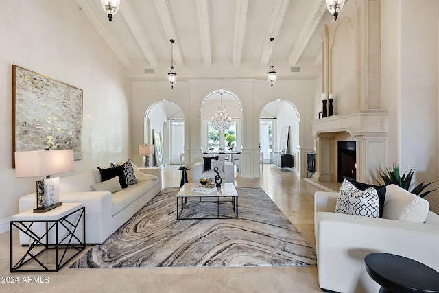 living room with light tile patterned flooring, a high ceiling, a fireplace, beam ceiling, and a chandelier