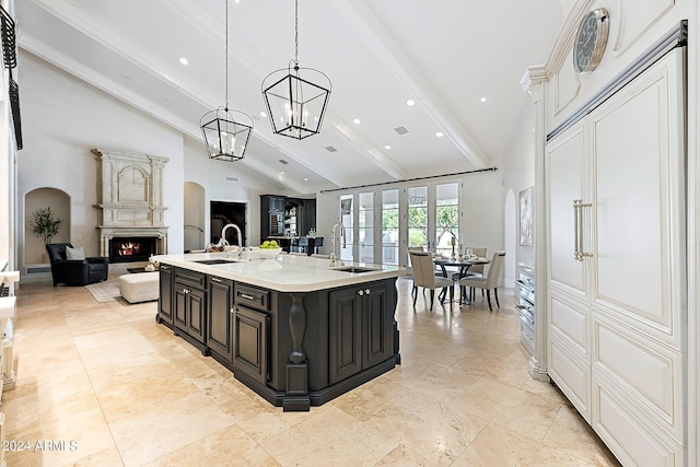 kitchen featuring hanging light fixtures, vaulted ceiling with beams, a kitchen island with sink, and sink