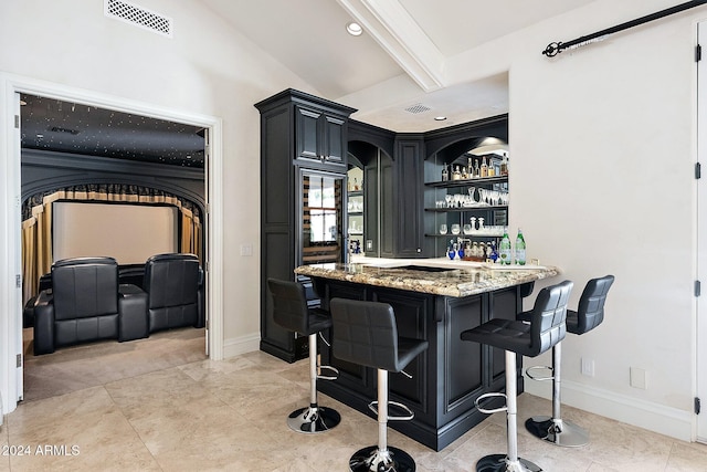 bar featuring built in features, lofted ceiling with beams, and light stone counters