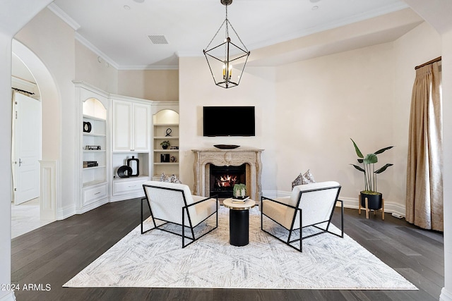 living room with a high end fireplace, built in shelves, a notable chandelier, and wood-type flooring