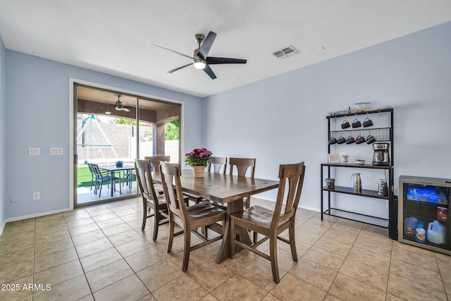 tiled dining area with a ceiling fan and baseboards