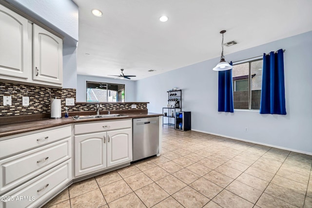 kitchen featuring dishwasher, a sink, dark countertops, decorative backsplash, and light tile patterned floors