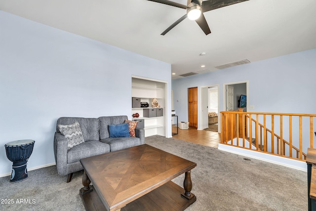 carpeted living area featuring ceiling fan, baseboards, and tile patterned floors