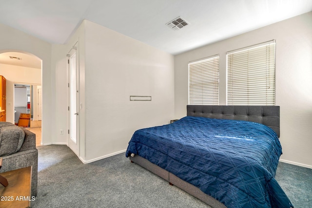 carpeted bedroom featuring arched walkways and baseboards