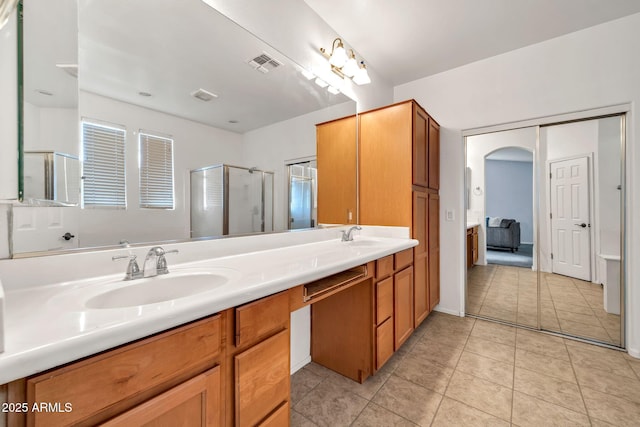 bathroom with tile patterned flooring, a shower stall, and double vanity