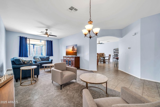 living room with ceiling fan, arched walkways, a chandelier, tile patterned floors, and baseboards
