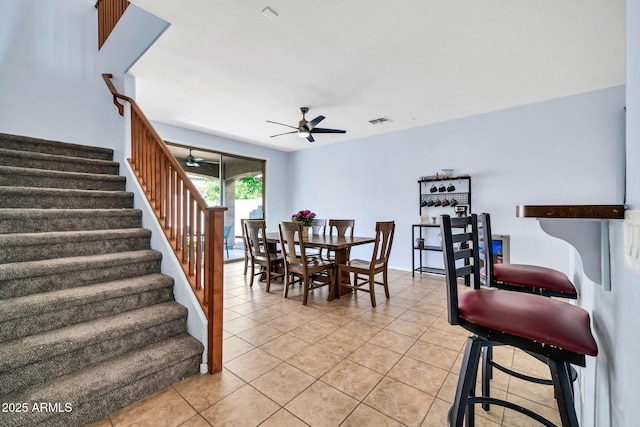dining space with a ceiling fan, stairway, and light tile patterned flooring