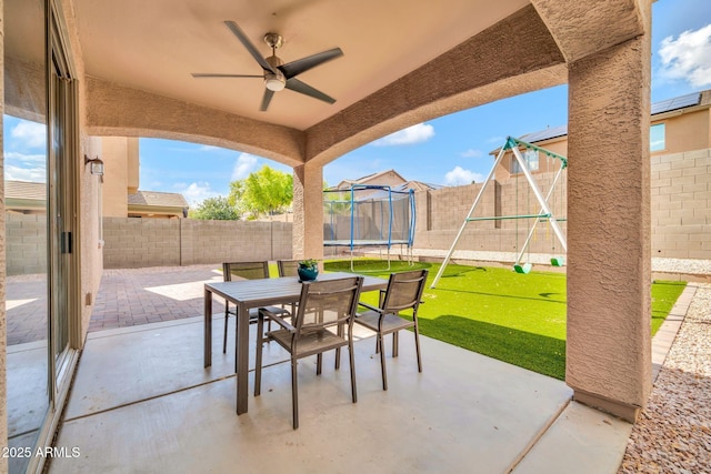view of patio with a playground, a trampoline, outdoor dining area, and a ceiling fan