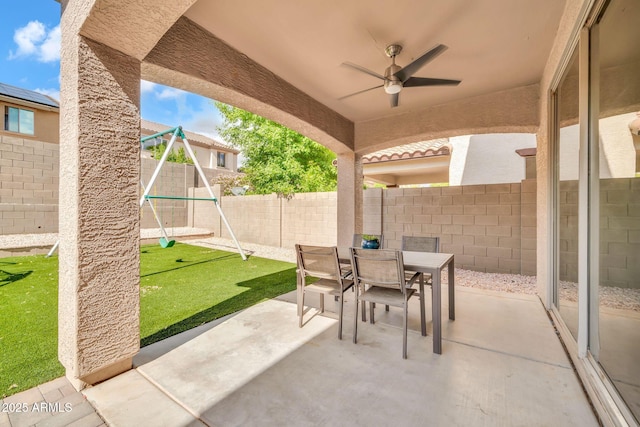 view of patio with outdoor dining space, a fenced backyard, ceiling fan, and a playground