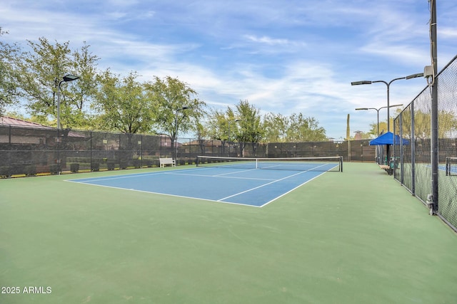 view of tennis court featuring fence and community basketball court