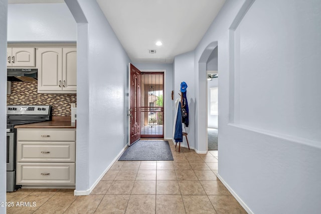 entrance foyer with arched walkways, light tile patterned flooring, baseboards, and recessed lighting