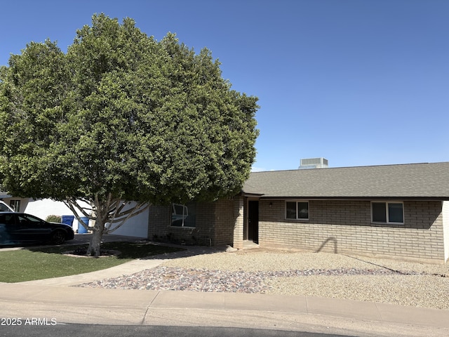 view of front of property featuring brick siding and roof with shingles