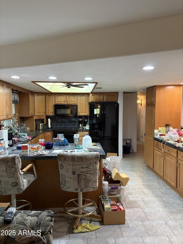 kitchen featuring black appliances, a kitchen breakfast bar, dark countertops, decorative backsplash, and brown cabinets