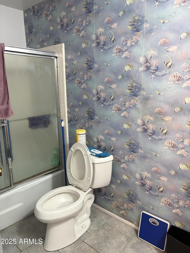 bathroom featuring tile patterned flooring, toilet, enclosed tub / shower combo, baseboards, and wallpapered walls