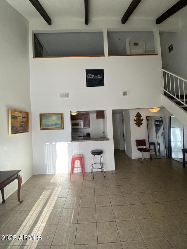 living area with a high ceiling, beamed ceiling, and tile patterned flooring