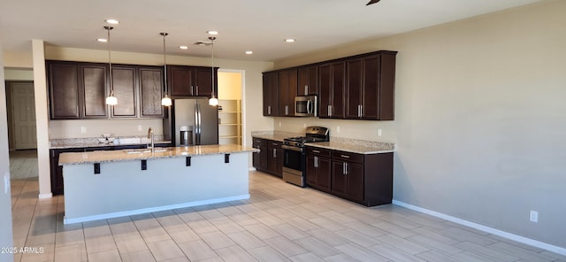 kitchen featuring stainless steel appliances, an island with sink, pendant lighting, and a breakfast bar area