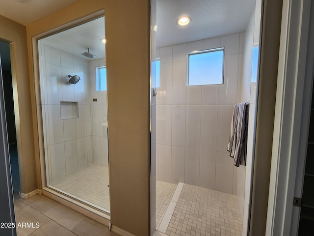 bathroom featuring tile patterned flooring and a tile shower