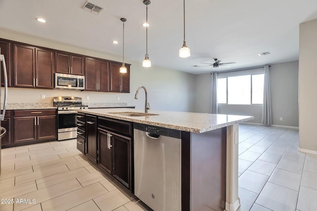 kitchen featuring appliances with stainless steel finishes, an island with sink, sink, hanging light fixtures, and dark brown cabinetry