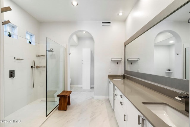 bathroom featuring toilet, a tile shower, and vanity