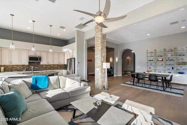 living room with ceiling fan, sink, light hardwood / wood-style flooring, and ornate columns