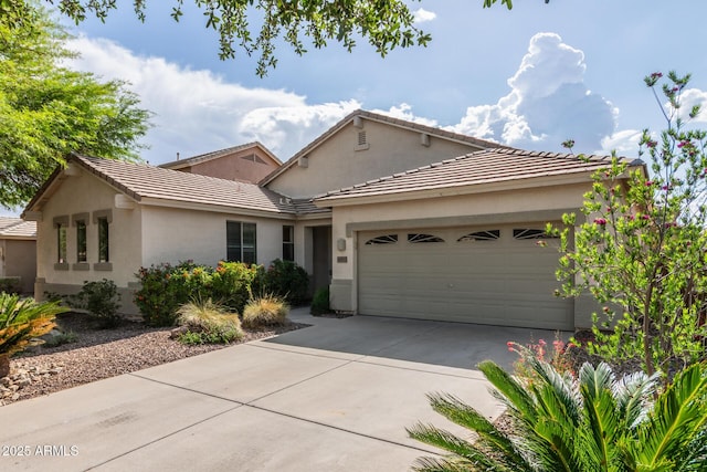 view of front of property featuring a garage, driveway, stucco siding, and a tile roof