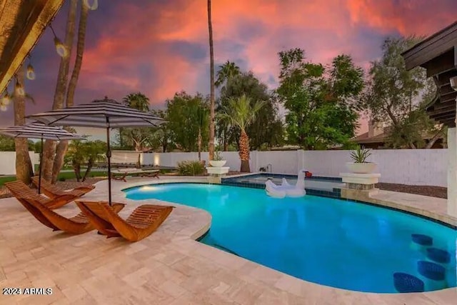 pool at dusk featuring a patio, a fenced backyard, a fenced in pool, and a hot tub