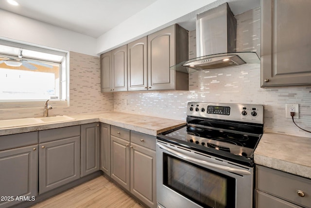 kitchen with gray cabinets, stainless steel electric range oven, wall chimney exhaust hood, and sink