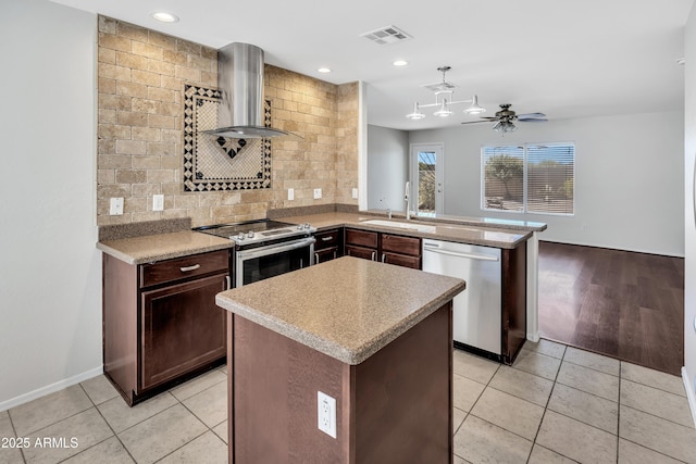 23075 W Arrow Dr, Buckeye, AZ 85326 - kitchen with stainless steel appliances, wall chimney range hood, decorative backsplash, a peninsula, and light countertops