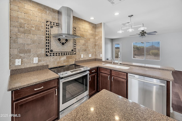 23075 W Arrow Dr, Buckeye, AZ 85326 - kitchen featuring stainless steel appliances, wall chimney range hood, dark brown cabinetry, decorative backsplash, and a peninsula