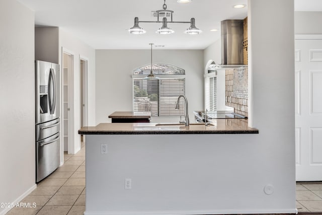 23075 W Arrow Dr, Buckeye, AZ 85326 - kitchen featuring stainless steel refrigerator with ice dispenser, wall chimney exhaust hood, light tile patterned floors, a peninsula, and pendant lighting