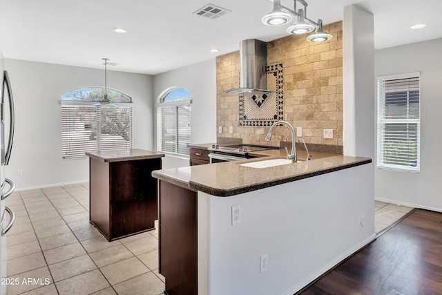 23075 W Arrow Dr, Buckeye, AZ 85326 - kitchen with wall chimney exhaust hood, a kitchen island, stainless steel electric range oven, tasteful backsplash, and decorative light fixtures