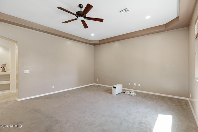 carpeted empty room with ceiling fan and a raised ceiling