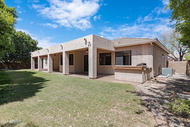 rear view of property with central AC unit, ceiling fan, a lawn, and a patio