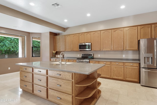 kitchen featuring light tile patterned floors, appliances with stainless steel finishes, a center island with sink, and sink