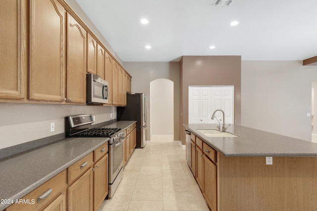 kitchen featuring sink, light tile patterned floors, stainless steel appliances, and an island with sink