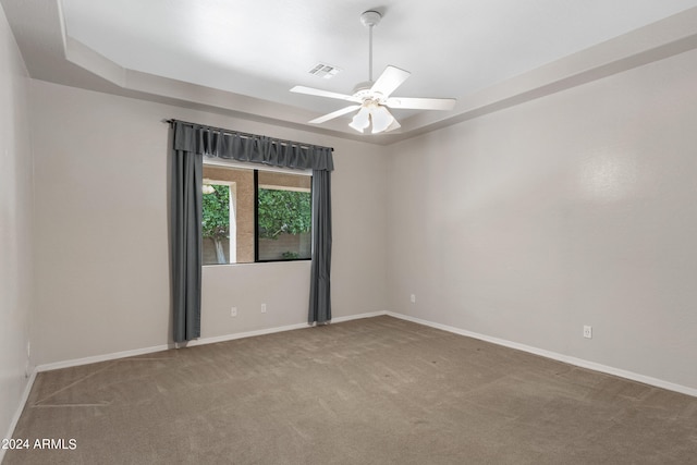 carpeted empty room with ceiling fan and a tray ceiling