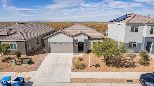 view of front of home with an attached garage, a tiled roof, concrete driveway, and stucco siding