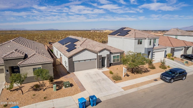 view of front of house with a residential view, roof mounted solar panels, driveway, and stucco siding