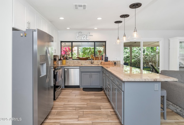 7806 N Via Del Sol, Scottsdale, AZ 85258 - kitchen with appliances with stainless steel finishes, gray cabinetry, a peninsula, light stone counters, and a breakfast bar area