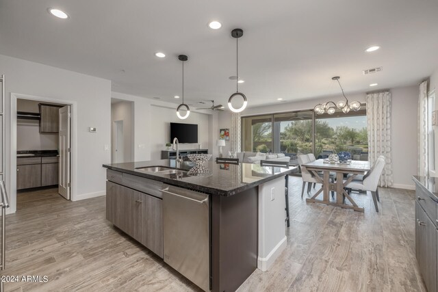 kitchen featuring pendant lighting, light hardwood / wood-style floors, sink, a center island with sink, and stainless steel dishwasher