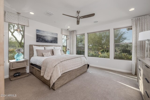 bedroom featuring multiple windows, light carpet, and ceiling fan