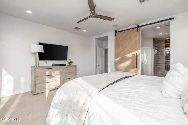 bedroom with ceiling fan, light colored carpet, and a barn door