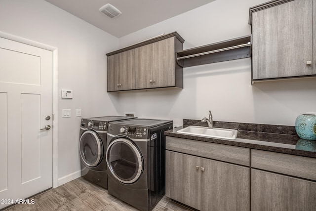 washroom featuring cabinets, sink, and washing machine and dryer