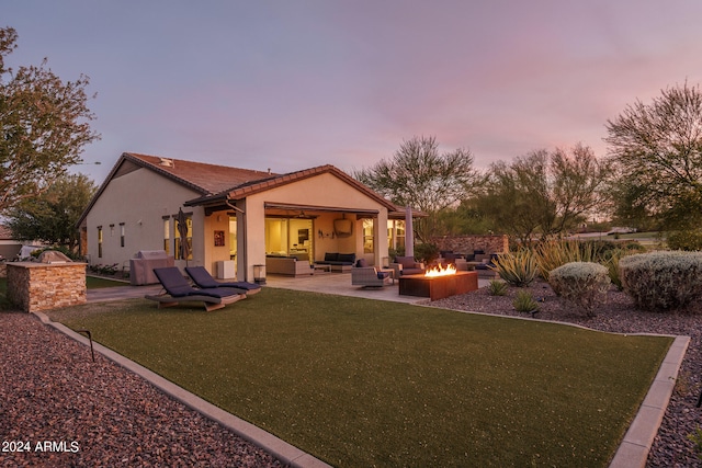 back house at dusk with an outdoor living space with a fire pit, a yard, and a patio