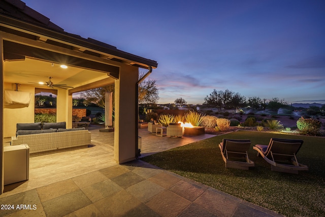 patio terrace at dusk with outdoor lounge area, a yard, and ceiling fan