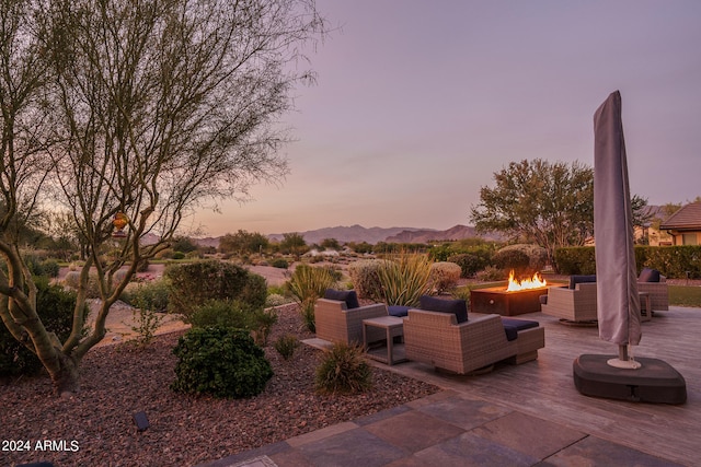 patio terrace at dusk featuring a mountain view and an outdoor living space with a fire pit