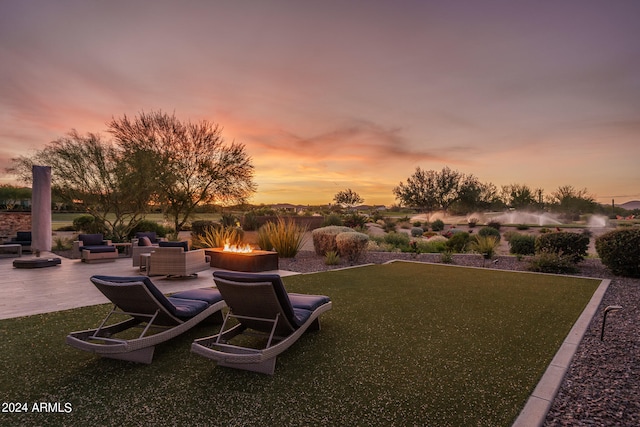 yard at dusk featuring a patio and a fire pit